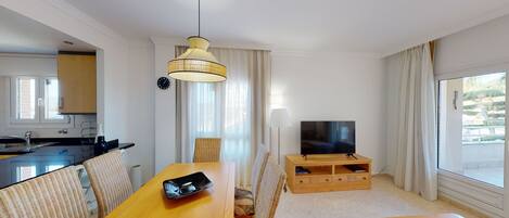A modern hotel room with a dining area, a TV, and a view of the outdoors.