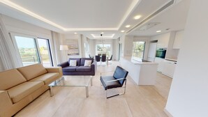Un saló modern amb un sofà, una taula de centre i una zona de menjador amb cadires.