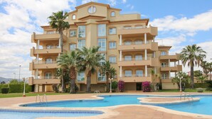 Un hotel de varios pisos con piscina, palmeras y cielo despejado.