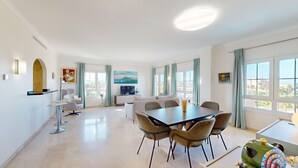 En moderne stue med spiseplads, store vinduer og udsigt over byen.