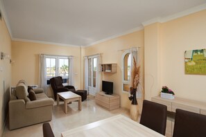 Una sala de estar con sofá, televisor y comedor.