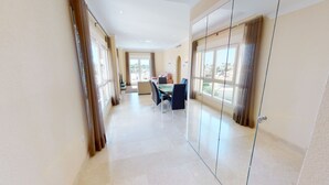 A spacious hallway with a dining area, large windows, and a view of the outside.