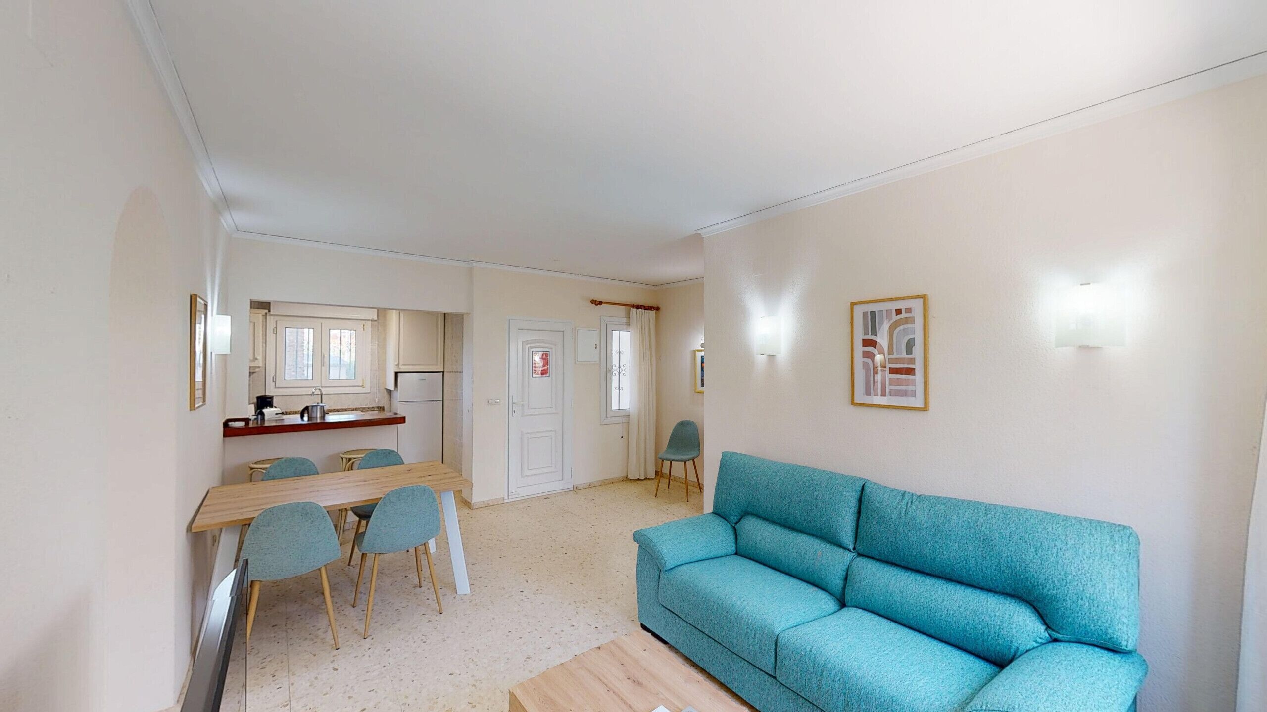 A compact living space with a dining area, kitchenette, and a sofa.