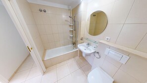 Ein Badezimmer mit einer Badewanne, einem Waschbecken, einer Toilette und einer Duschkabine aus Glas.
