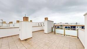 A rooftop terrace with tiled flooring, white walls, and multiple chimneys. - Lily by ON Travel (Oliva)