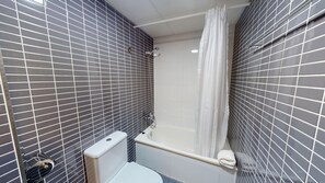 A small bathroom with a toilet, a bathtub, and a shower. - Lily by ON Travel (Oliva)