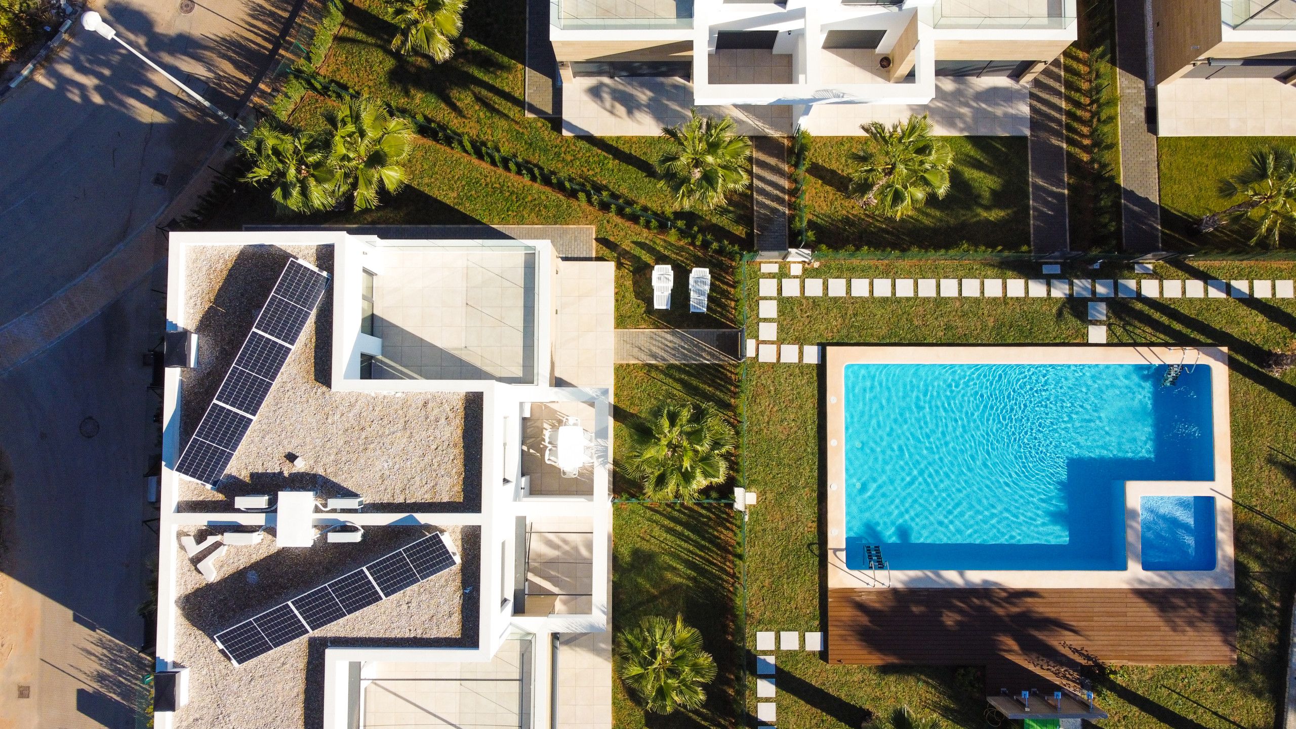 Vista aérea de un área residencial con piscina, paneles solares y césped bien cuidado.