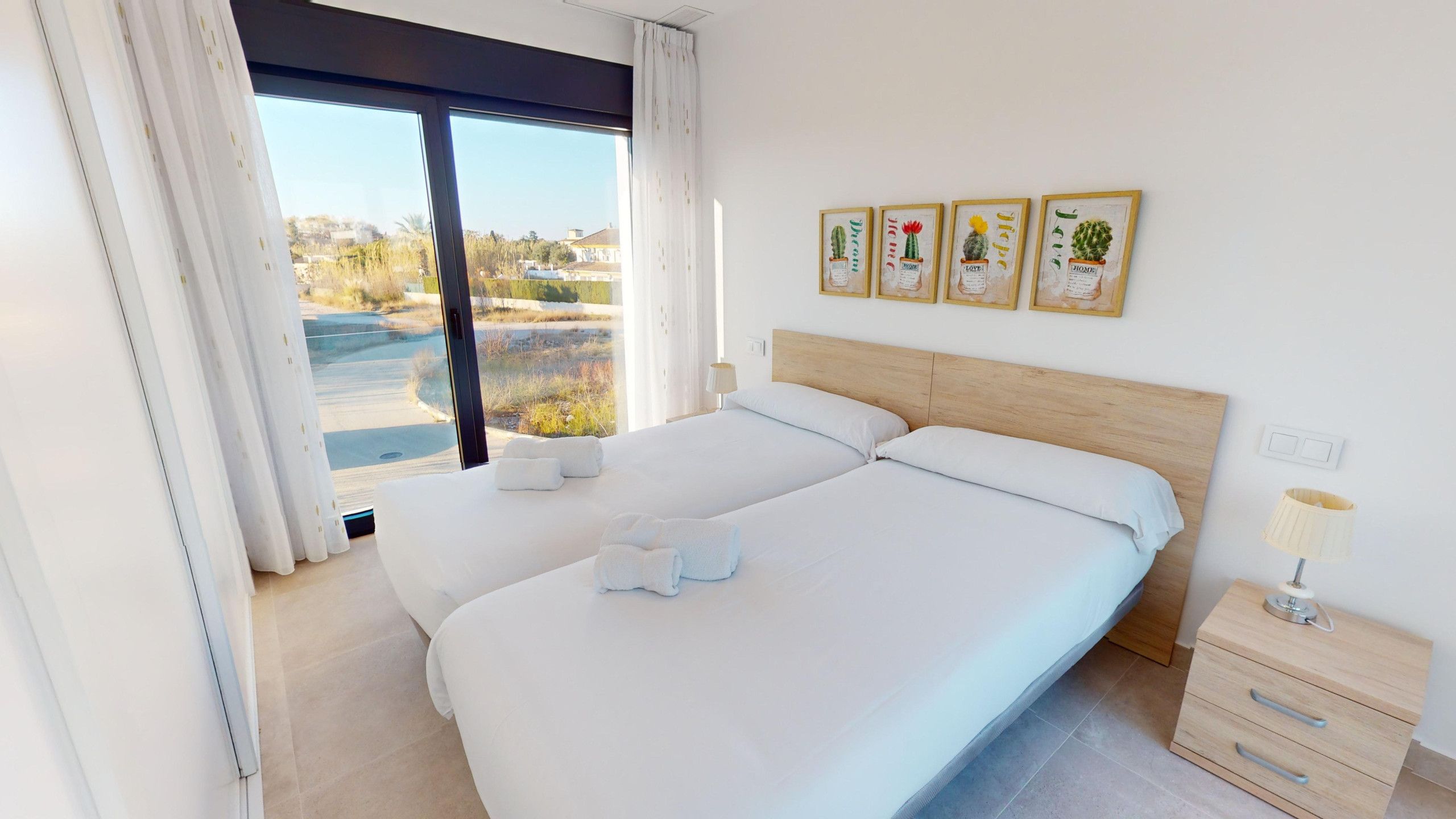 Een slaapkamer met een groot bed, een nachtkastje, een lamp en uitzicht op een waterpartij door het raam.