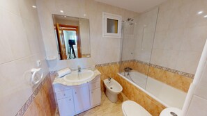 Een badkamer met een wastafel, toilet, bidet en bad.