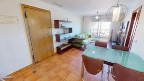 Un comedor con una mesa de vidrio y sillas marrones, una puerta de madera y piso de baldosas.