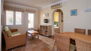 Una sala de estar amoblada con un sofá, una mesa y un televisor.