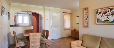 Un coin repas avec des meubles en osier, un canapé et un tableau accroché au mur.