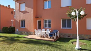 A two-story building with a patio area featuring a table and chairs, a sun lounger, and a street lamp. - Velvet by ON Travel (Oliva)