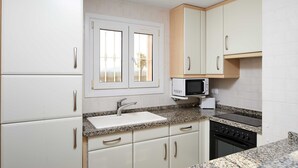 A kitchen with white cabinets, a granite countertop, a microwave, a stove, and a sink. - Yarrow by ON Travel (Oliva)
