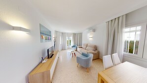 Een moderne hotelkamer met een bank, fauteuils, een eettafel en een televisie.