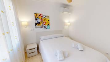 Une chambre d’hôtel comprenant un lit, une table de chevet, un climatiseur fixé au mur et un mur orné de différents panneaux.
