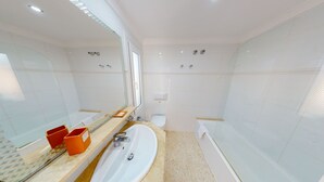 Een moderne badkamer met een groot wastafel, spiegel en een bad.