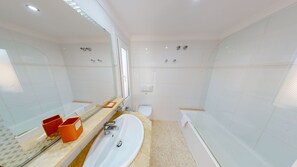Une salle de bain moderne avec un grand miroir, un lavabo, des toilettes et une baignoire.