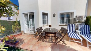 Une terrasse extérieure avec une table ronde, six chaises et deux fauteuils de relaxation.