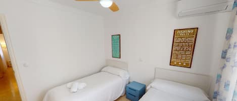 A hotel room with two single beds, a small blue nightstand, and two wall-mounted signs with text.