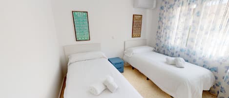A hotel room with two single beds, a blue storage box, and two wall-mounted signs with rules.