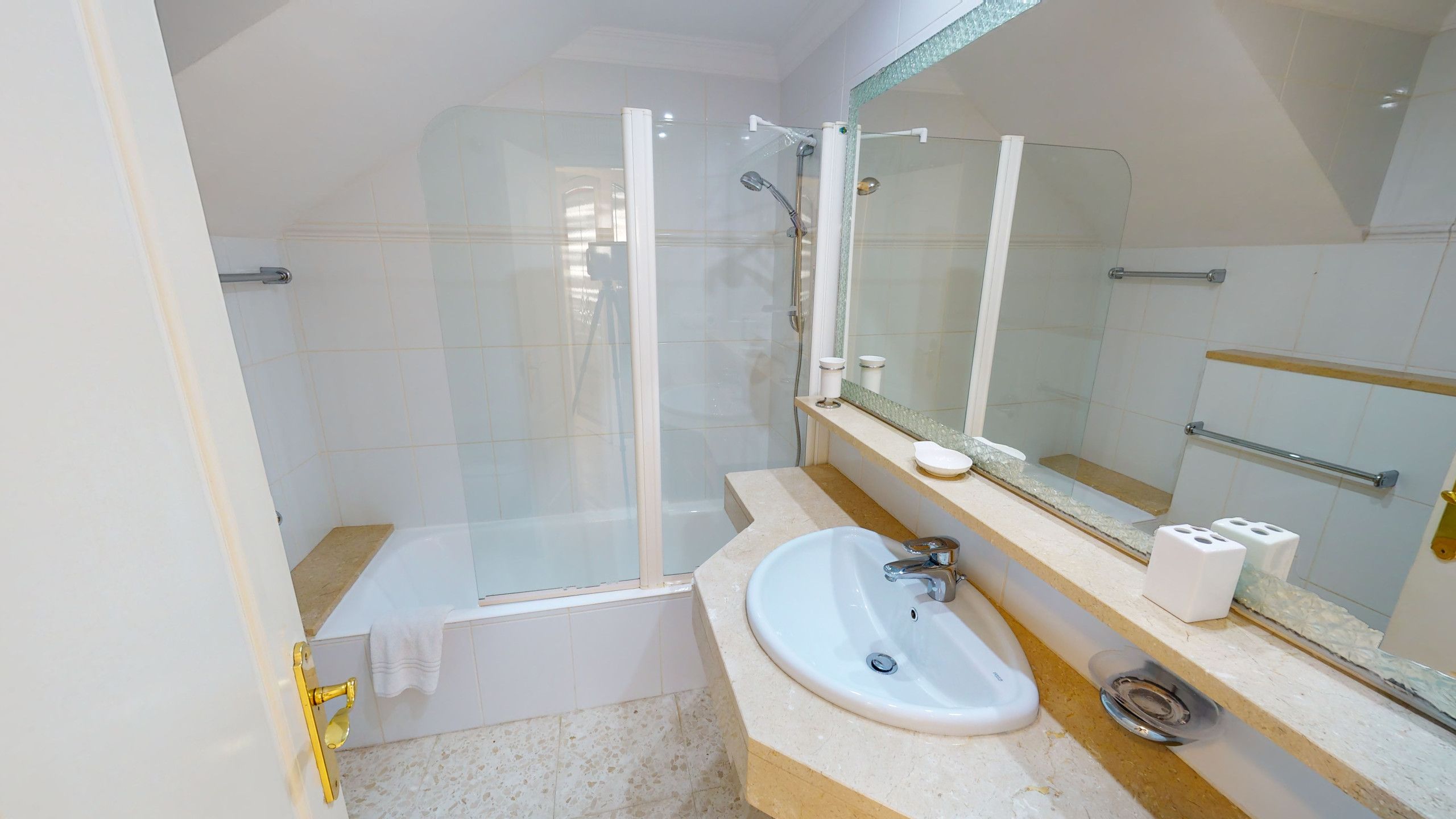 Une salle de bain moderne avec une douche à parois de verre, un lavabo blanc et un grand miroir.