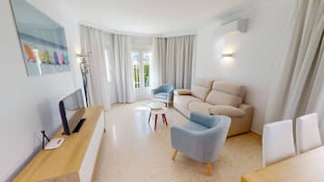 Un salon moderne avec un canapé, des fauteuils, une table basse et un téléviseur.