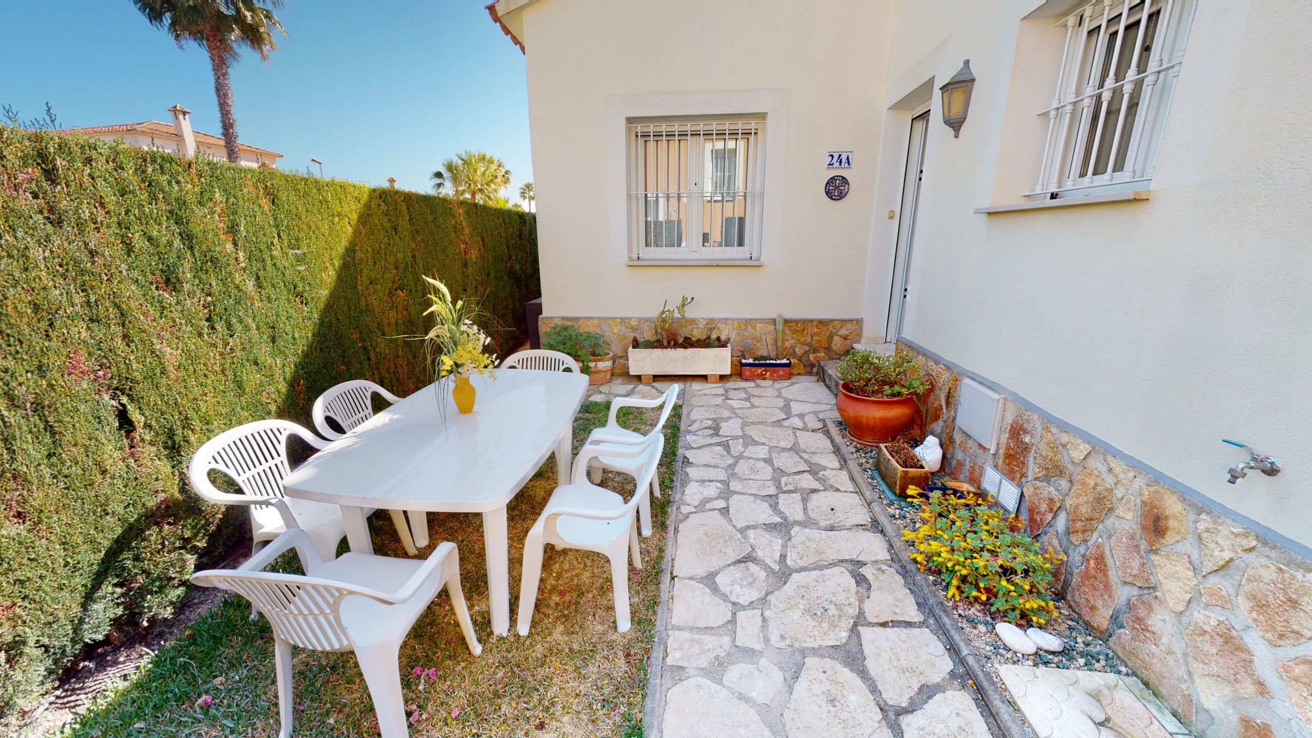 A patio with a table and chairs, a stone pathway, and potted plants.