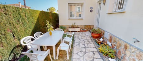 A patio with a table and chairs, a stone pathway, and potted plants.