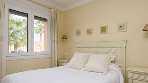 A bedroom with a bed, a nightstand, a lamp, and a window with curtains. - Maestral by ON Travel (Oliva)