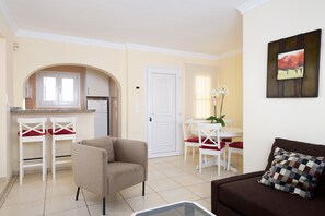Um espaço compacto com cozinha compacta, área de refeições e sala de estar com sofá e cadeiras.