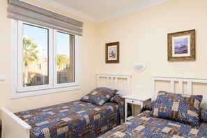 A bedroom with two beds, a window with blinds, and two framed pictures on the wall. - Poniente by ON Travel (Oliva)