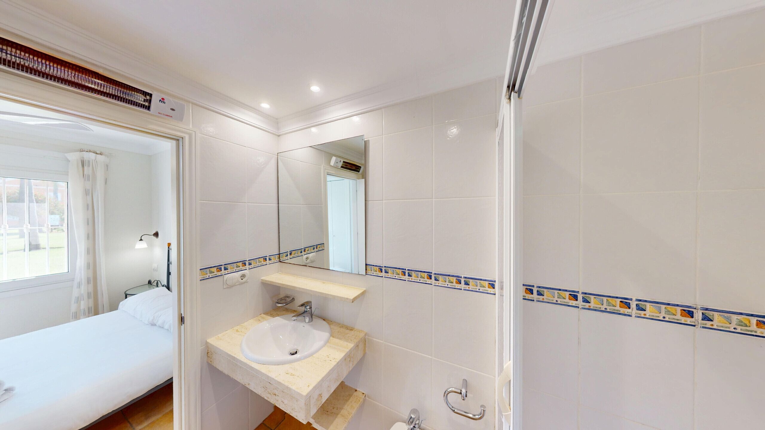 Een hotelbadkamer met een wastafel, spiegel en douche.