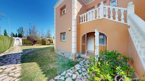 Ein zweistöckiges Haus mit einem Kiesweg, der zum Eingang führt, einem weißen Tor und einem kleinen Garten.
