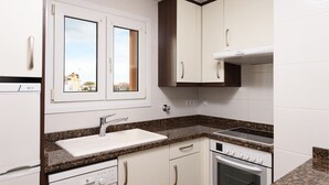 Een moderne keuken met witte kasten, een granieten aanrechtblad, een inbouwoven en een raam met uitzicht.