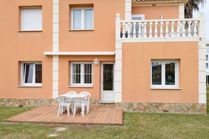 A two-story building with a tiled patio, white-framed windows, and a stone base. - Gazania by ON Travel (Oliva)