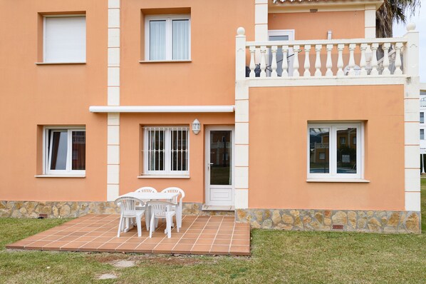 Un bâtiment à deux étages doté d’un patio carrelé, de fenêtres à cadre blanc et d’une base en pierre.