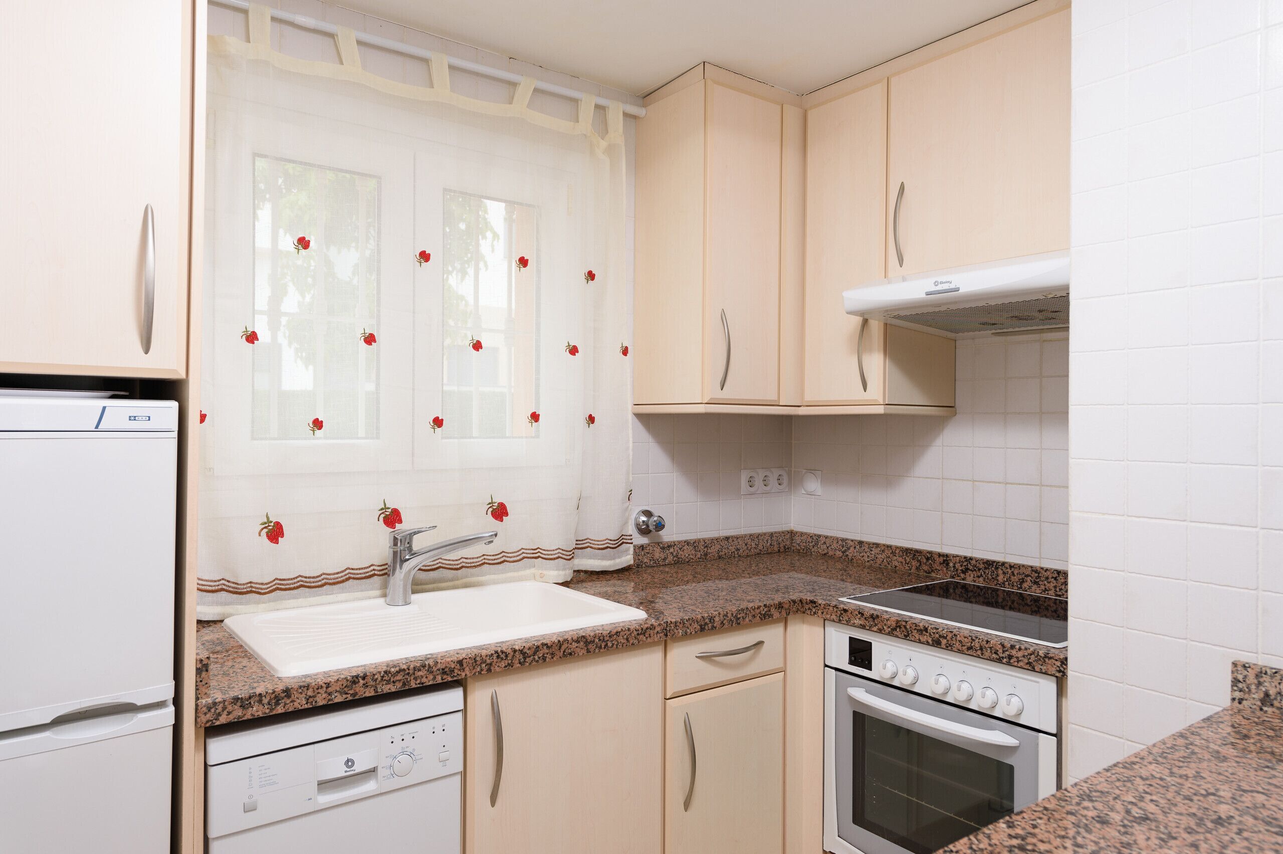 A kitchen with a built-in dishwasher, a stove, and a sink.