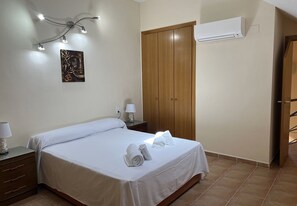 A bedroom with a bed, two bedside tables, a wardrobe, an air conditioner, and a wall-mounted artwork. - Penthouse in Denia (Denia)