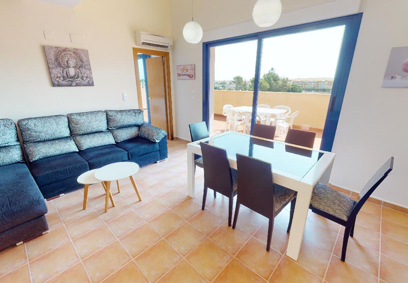 Een woonkamer met een bank, een eettafel met stoelen en een groot raam.
