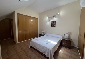 A bedroom with a bed, nightstands, a wardrobe, and a wall-mounted light fixture.