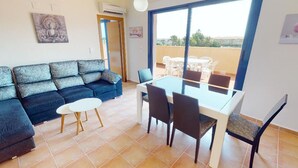 A living room with a sofa, a dining table with chairs, and a large window. - Penthouse in Denia (Denia)