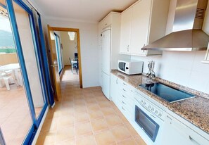 A kitchen with white cabinets, a microwave, a stove, and a sink. - Penthouse in Denia (Denia)