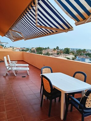 A rooftop terrace with a table and chairs, striped awnings, and a view of the cityscape. - Penthouse in Denia (Denia)