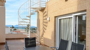 Una terrazza con tavolo e sedie, una scala a chiocciola e vista sul mare.