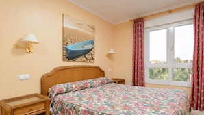 Una camera da letto con un letto, due comodini, una lampada a parete, un quadro e una finestra con tende.