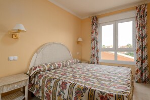A bedroom with a bed, two wall-mounted lamps, a window with curtains, and a small bedside table. - Denia Beachfront apartment by ON Travel (Denia)