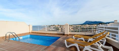 Una piscina en la azotea con vistas al mar y a las montañas.