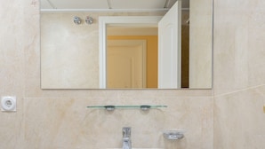 Un bagno con un lavandino bianco, uno specchio sopra e un portasciugamani con asciugamani.