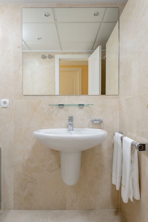 A bathroom with a white sink, a mirror above it, and a towel rack with towels. - Denia Beachfront apartment by ON Travel (Denia)